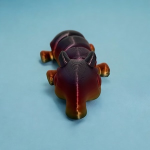 Puede incluir: Una figura de hormiga impresa en 3D con un degradado de color negro y rojo. La hormiga está en posición de arrastre con la cabeza hacia abajo y las patas visibles.