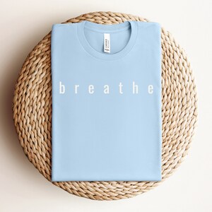 May include: A light blue t-shirt with the word "breathe" printed in white on the front.