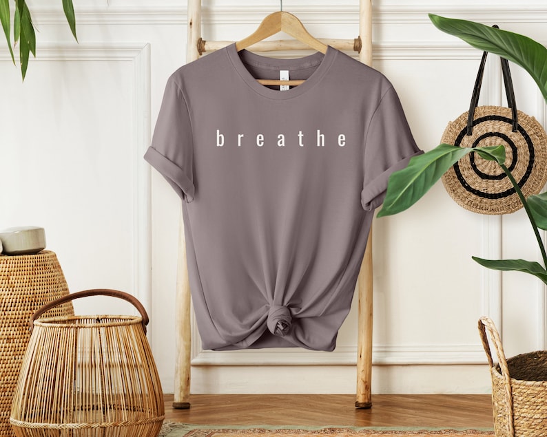 May include: A mauve colored t-shirt with the word "breathe" printed in white on the front.