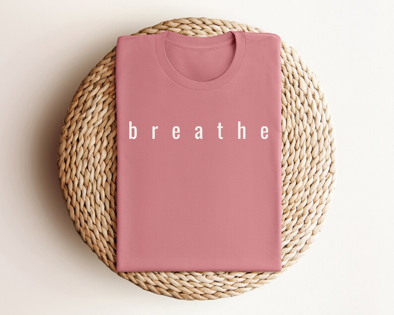 May include: A folded pink t-shirt with the word "breathe" printed in white on the front.