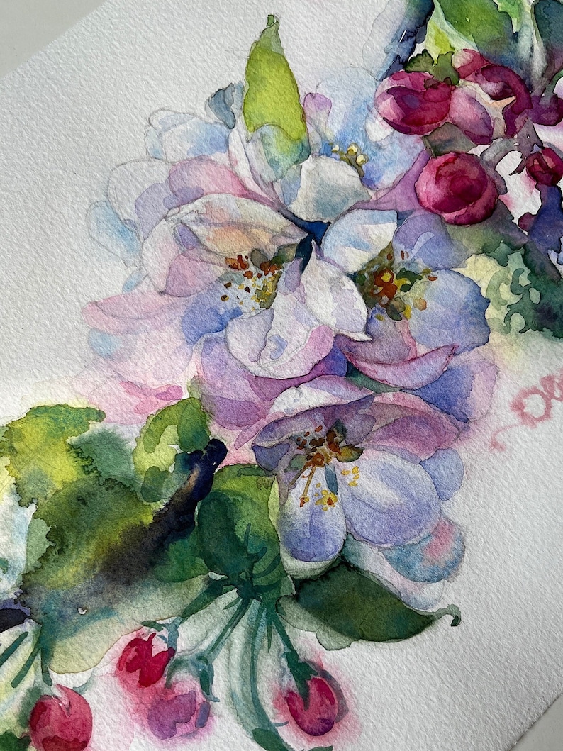 Close-up of pink watercolor apple flowers with delicate petals, green leaves, and soft blue background details.