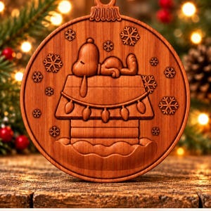 May include: A round wooden Christmas ornament featuring a carved relief of a dog sleeping on top of a doghouse decorated with string lights, surrounded by snowflakes. The text at the bottom reads: Digital CNC File - No Physical Product.