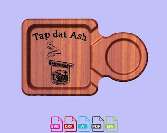 May include: A wooden tray with a cutout for a drink and a small round dish for ashes. The tray is engraved with the text "Tap dat Ash" and a design of a glass with a cigar and smoke.