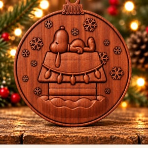 May include: A round wooden ornament featuring a carved Snoopy lying on top of a doghouse, surrounded by snowflakes and string lights. The ornament has a loop at the top for hanging. The text at the bottom reads: Digital CNC File - No Physical Product.