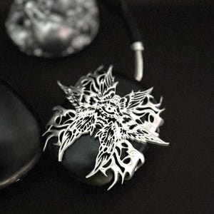 May include: A black and silver headphone with a decorative, intricate, silver, floral design on the earcup.