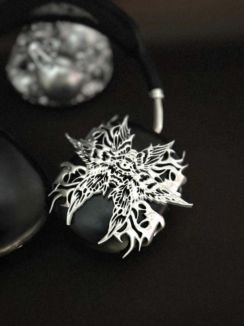 May include: A black and silver headphone with a decorative, intricate, silver, floral design on the earcup.