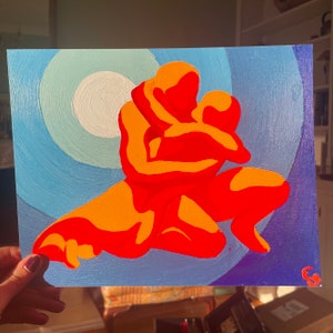 May include: An abstract painting depicts two figures embracing, rendered in shades of orange and red against a backdrop of concentric blue circles. The artwork evokes a sense of warmth and connection, with a white center.
