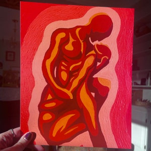 May include: An abstract painting featuring a figure in shades of red, orange, and peach. The artwork depicts a person in a contemplative pose, with a gradient background. The painting is held by a hand with a purple nail polish.