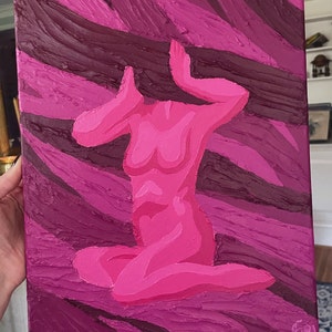 May include: A pink abstract painting of a seated figure with arms raised. The figure is rendered in varying shades of pink against a textured background of dark and light pink brushstrokes. The artwork is on a canvas.