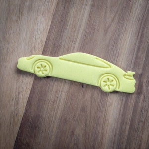 May include: A yellow car cutout on a wood background.