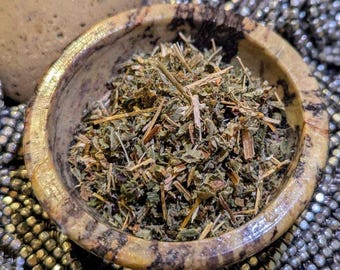 May include: A close-up of dried herbs in a small, brown, speckled bowl. The bowl is made of natural stone and has a rough texture.