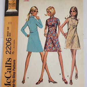 Op de afbeelding: Een McCall's 2206 naaipatroon-envelop met illustraties van drie jurkversies: een effen lichtblauwe jurk met lange mouwen, een jurk met korte mouwen met een rood en blauw bloemenpatroon, en een mouwloze, getextureerde beige jurk.