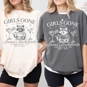 May include: Two oversized t-shirts, one cream and one charcoal, featuring a raccoon illustration with cocktails. The shirts read "GIRLS GONE FERAL" and "Ariana's Bachelorette, Nashville, TN, May 2025."