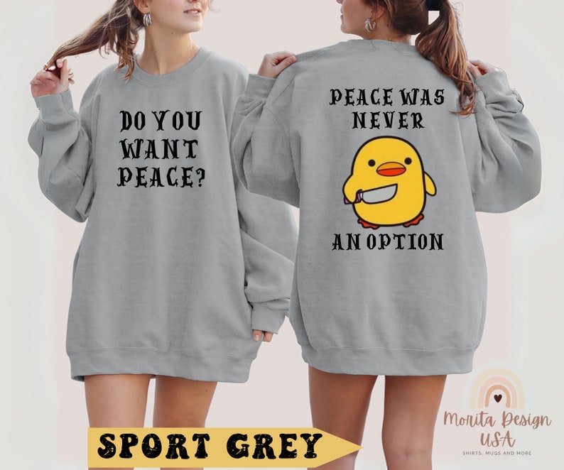 K&ouml;nnte beinhalten: Ein graues Sweatshirt mit dem Text "Do you want peace?" auf der Vorderseite und "Peace was never an option" mit einem Cartoon-K&uuml;ken, das ein Messer h&auml;lt, auf der R&uuml;ckseite. Das Sweatshirt ist in Sportgrau gehalten.