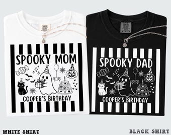 May include: A white t-shirt with black print and a black t-shirt with white print, both featuring vertical stripes and a graphic of a ghost, cat, pumpkin, cake, and candy with the text SPOOKY MOM, SPOOKY DAD, and COOPER'S BIRTHDAY.