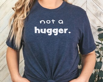 May include: A navy blue t-shirt with the text "not a hugger." printed in white.