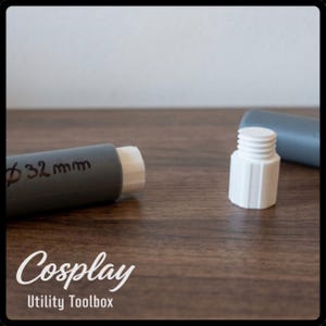 Può includere: Un tubo cilindrico grigio con il testo 32mm scritto sul lato e un'estremità filettata bianca. Un componente separato in plastica bianca con una parte superiore filettata e una base esagonale si trova vicino, accanto a un altro segmento di tubo grigio.