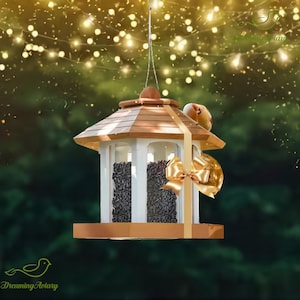 May include: A wooden bird feeder with a brown roof and white frame, filled with black seeds. A gold ribbon and bow adorn the feeder. A small bird perches on the roof. The feeder hangs from a thin wire against a blurred green background.