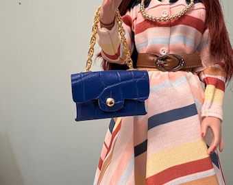 May include: A small blue purse with a gold chain strap and a crocodile-embossed texture. The purse has a gold button closure.