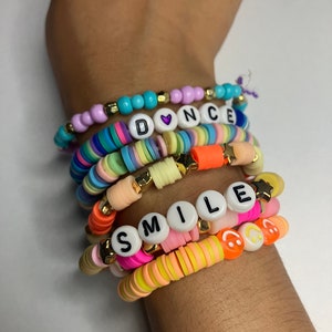 May include: A stack of colourful beaded bracelets with letter beads spelling out "DANCE" and "SMILE". The bracelets also feature heart, star and smiley face beads.