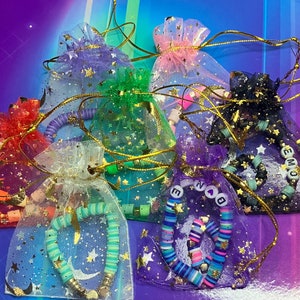 May include: An assortment of colourful star-shaped mesh bags with beaded necklaces and charms. The bags are made of a soft, sheer fabric and feature a variety of colours, including pink, green, purple, and black. The necklaces are made of colourful beads and feature charms, such as stars, hearts, and letters.