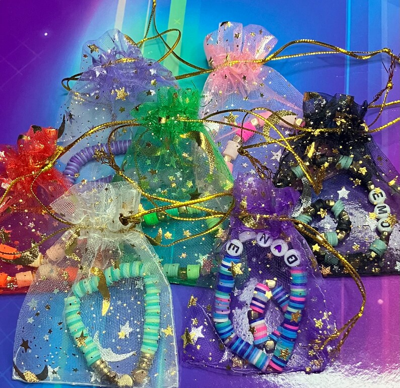 May include: An assortment of colourful star-shaped mesh bags with beaded necklaces and charms. The bags are made of a soft, sheer fabric and feature a variety of colours, including pink, green, purple, and black. The necklaces are made of colourful beads and feature charms, such as stars, hearts, and letters.