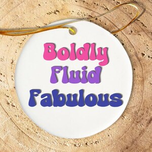 May include: White ceramic ornament with the text "Boldly Fluid Fabulous" in pink, purple, and blue retro font.