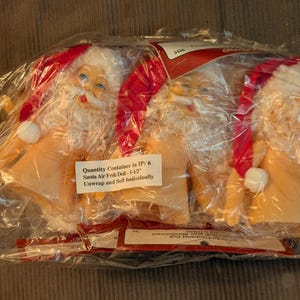 May include: A package containing six Santa Air Fish Dolls, each 5.5 inches tall. The dolls are in a clear plastic bag. Each doll has a red hat, white beard, and a smiling face. The package includes a label that reads "Unwrap and Self Individually."