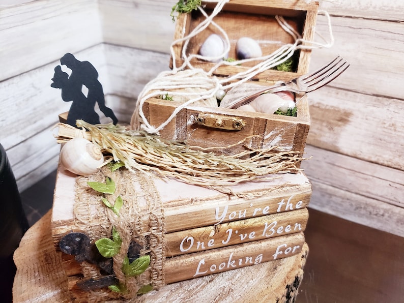 K&ouml;nnte beinhalten: Eine Holzkiste mit einer Silhouette eines tanzenden Paares auf der Oberseite. Die Kiste ist mit Muscheln, Schnur und Moos verziert. Die Kiste steht auf einem Stapel B&uuml;cher mit den Worten "You're the One I've Been Looking For" darauf.