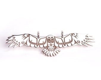 May include: A silver pendant in the shape of an eagle with its wings spread out. The eagle is stylized with a geometric design and has a detailed face.