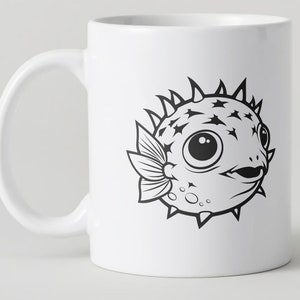 May include: A white ceramic mug with a black and white illustration of a pufferfish. The pufferfish has a spiky exterior and large, round eyes.