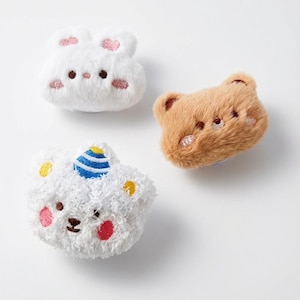 May include: Three plush, cartoon-style animal face patches. A white bunny with pink accents, a brown bear, and a white bear with a blue and yellow hat. Each has embroidered facial features and pink or red cheeks.