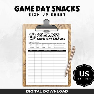 Peut inclure: Une feuille d'inscription imprimable pour les collations du jour de match de football. La feuille comporte un graphique de ballon de football noir et blanc et le texte "Soccer Game Day Snacks". La feuille comprend des colonnes pour la date, l'heure, le joueur/parent et la collation/boisson.