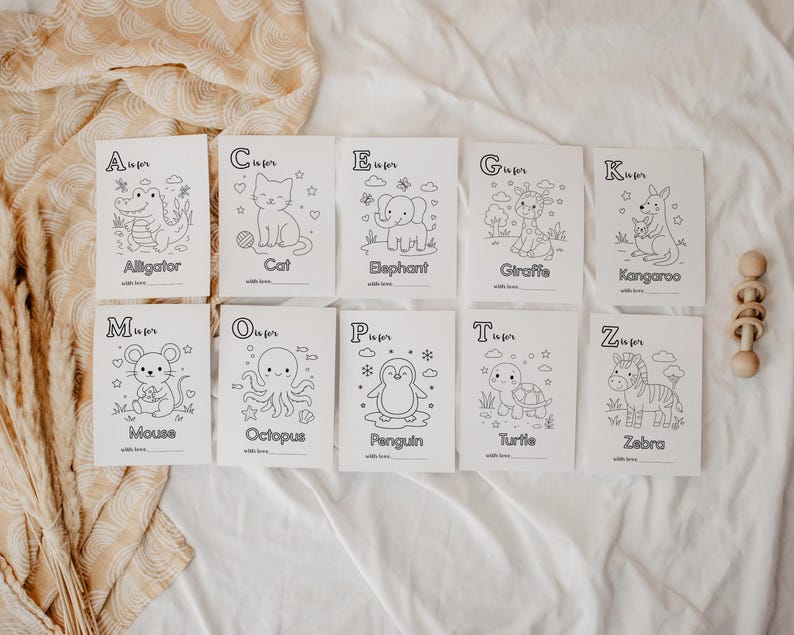 May include: A set of ten white cards with black line drawings of animals, each labeled with a letter of the alphabet. The animals include an alligator, cat, elephant, giraffe, kangaroo, mouse, octopus, penguin, turtle, and zebra. A wooden toy is on the right.
