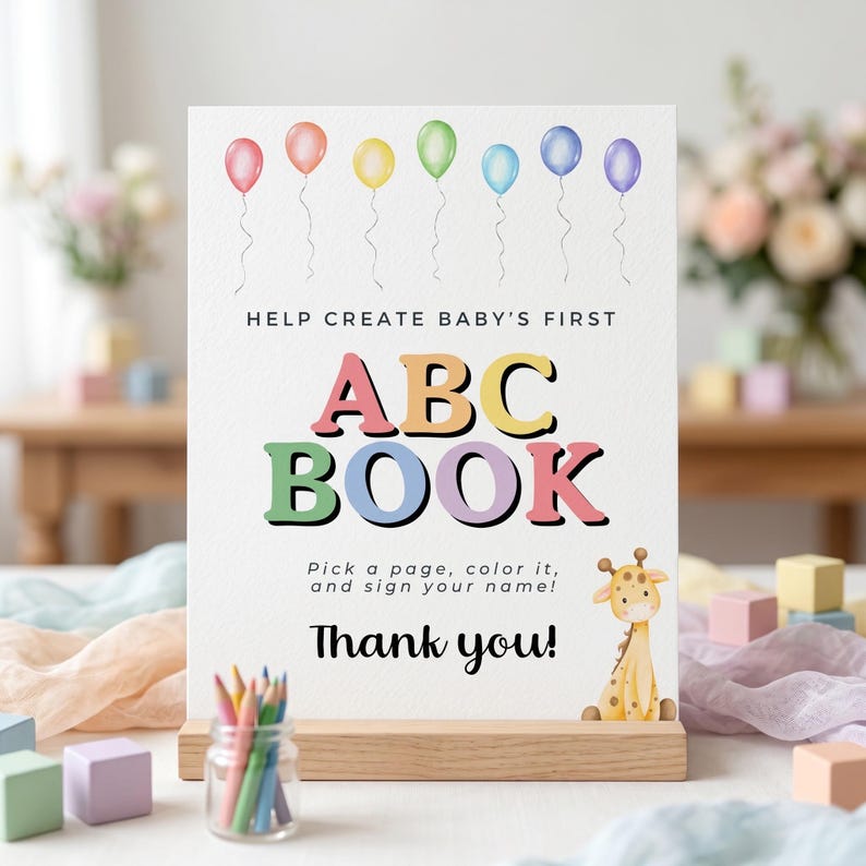 May include: A sign for a baby's first ABC book, featuring colorful balloons and the text "ABC BOOK." It includes instructions to color a page and sign your name, with a giraffe illustration and the words "Thank you!"