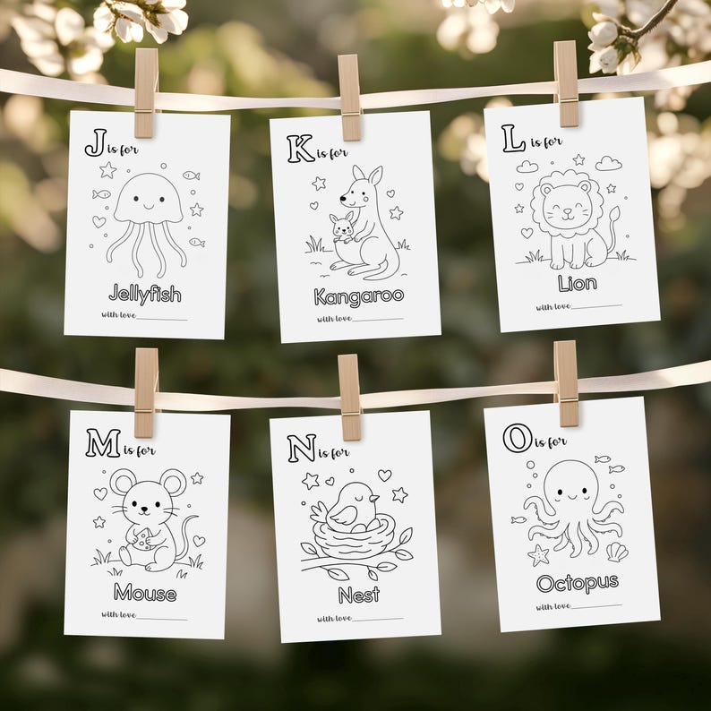 May include: Six white cards with black line drawings of animals and objects, each card is held by a wooden clothespin. The cards feature a jellyfish, kangaroo, lion, mouse, nest, and octopus. Each card has the letter of the alphabet and the word for the image.