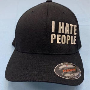 May include: Black Flexfit baseball cap with the embroidered text "I HATE PEOPLE" in white. The hat has a curved brim and a small Flexfit label. The hat is size S/M.