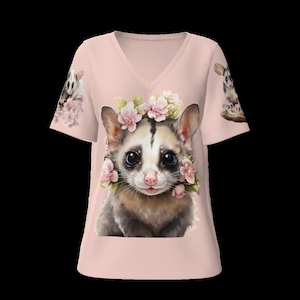 Op de afbeelding: Een roze t-shirt met een schattige illustratie van een suikerzweefvlieg die een bloemenkrans draagt. De suikerzweefvlieg zit op een roze achtergrond.