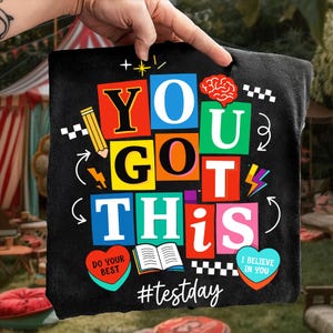 May include: Black tote bag with the words "YOU GOT THIS" in colorful block letters. The design includes a pencil, brain, lightning bolt, and hearts with text. The hashtag #testday is at the bottom.