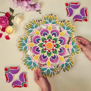 Può includere: Un mandala circolare colorato con un motivo a fiore di loto. Il mandala presenta sfumature di viola, verde, giallo e turchese. Sono visibili anche pezzi angolari aggiuntivi. L'immagine include anche fiori e una candela accesa.