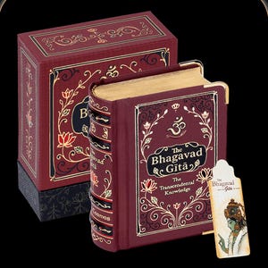 May include: A maroon-colored book titled "The Bhagavad Gita" with gold gilded edges and decorative floral and scroll designs. The book is in a matching maroon box with gold accents. A bookmark is included.