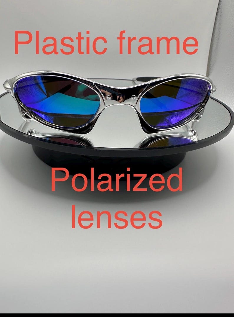 Op de afbeelding: Zonnebril met een zilverkleurig kunststof montuur en gepolariseerde glazen. De glazen hebben een blauwgroene reflecterende coating. Tekst op de afbeelding luidt "Kunststof montuur" en "Gepolariseerde glazen".