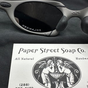 May include: A white card with black text and a black and white illustration of two angels. The text reads "Paper Street Soap Co. All Natural Handmade (288) 555-0153 537 Paper Street Bradford"