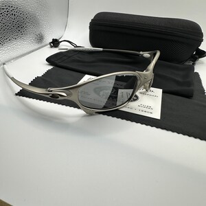 May include: Silver-toned sunglasses with a black case, black microfiber cloth, and a white tag. The sunglasses have a curved design and dark lenses. The case is rectangular and has a zipper. The tag has the text "PAPER STREET" and "TYLER DURDEN".