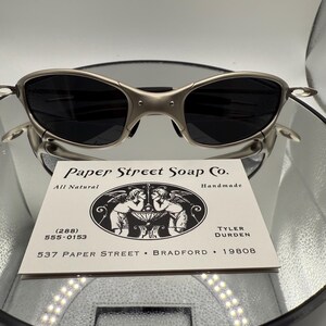 Peut inclure: Lunettes de soleil &agrave; monture argent&eacute;e avec verres fonc&eacute;s pos&eacute;es au-dessus d'une carte de visite. La carte indique "Paper Street Soap Co." avec les coordonn&eacute;es et l'adresse "537 Paper Street, Bradford, 19808."