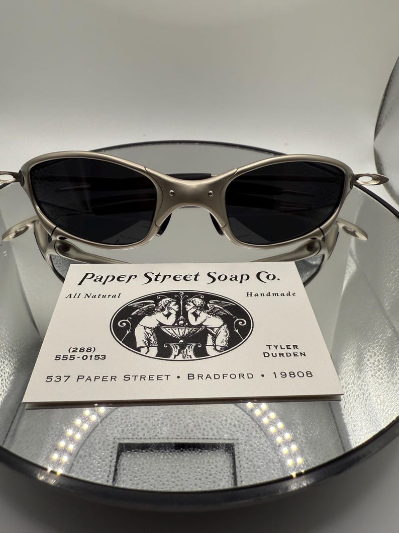 Peut inclure: Lunettes de soleil &agrave; monture argent&eacute;e avec verres fonc&eacute;s pos&eacute;es au-dessus d'une carte de visite. La carte indique "Paper Street Soap Co." avec les coordonn&eacute;es et l'adresse "537 Paper Street, Bradford, 19808."