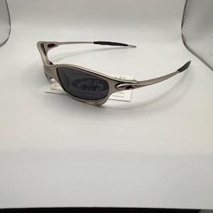 Peut inclure: Lunettes de soleil &agrave; monture argent&eacute;e avec verres fonc&eacute;s. Les lunettes de soleil ont un design &eacute;l&eacute;gant et moderne avec des branches incurv&eacute;es et une petite forme de lentille rectangulaire. Les verres semblent teint&eacute;s, et la monture est de couleur argent m&eacute;tallique.