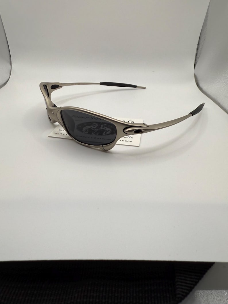 Peut inclure: Lunettes de soleil &agrave; monture argent&eacute;e avec verres fonc&eacute;s. Les lunettes de soleil ont un design &eacute;l&eacute;gant et moderne avec des branches incurv&eacute;es et une petite forme de lentille rectangulaire. Les verres semblent teint&eacute;s, et la monture est de couleur argent m&eacute;tallique.