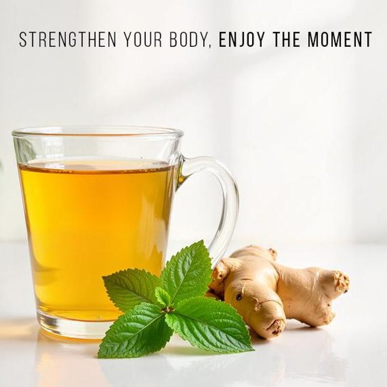 May include: A clear glass mug filled with golden-colored tea, accompanied by fresh green mint leaves and a piece of ginger root. The text "STRENGTHEN YOUR BODY, ENJOY THE MOMENT" is displayed at the top.