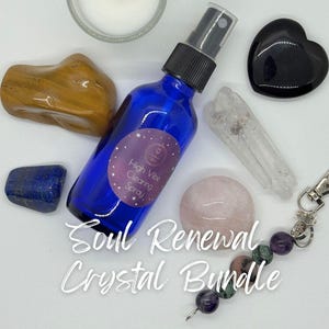 May include: A Soul Renewal Crystal Bundle featuring a blue spray bottle, a small candle, and various crystals. The crystals include a black heart-shaped stone, a clear quartz point, and a rose quartz sphere. The text "Soul Renewal Crystal Bundle" is displayed.